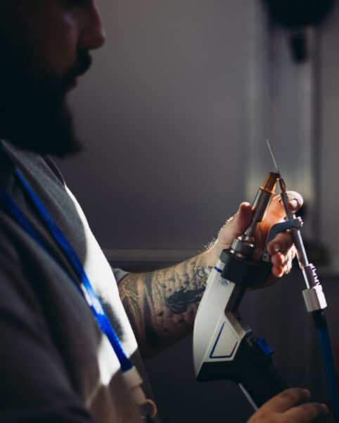profile of a standing man holding a dual wire feeder for laser welding